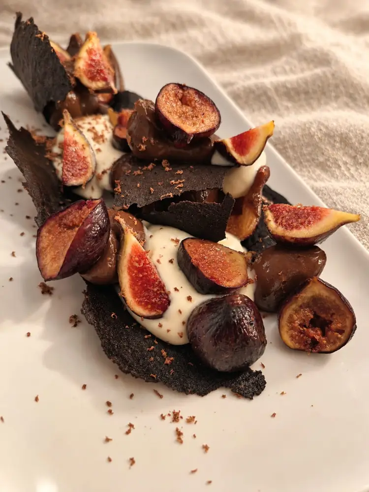 Figues, crème et croustillant au chocolat sur une planche sombre